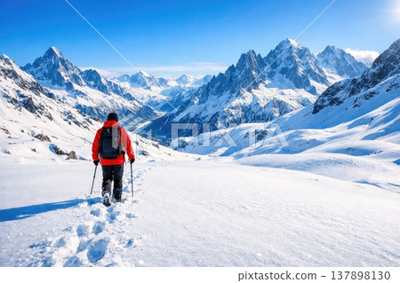 Hiker Walking Through Snowy Alpine Mountains Landscape with Backpack and Trekking Poles Hiker Walking Through Snowy Alpine Mountains Landscape with Backpack and Trekking Poles 137898130