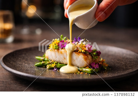 Gourmet Fish Fillet with Cream Sauce and Edible Flowers Served on Elegant Restaurant Plate 137898132