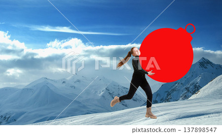 Woman walking in snowy mountain landscape carrying oversized red ornament ball. 137898547