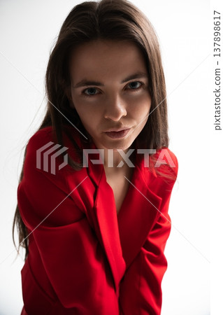 Young woman in a vibrant red blazer embodying confidence and strength, showcasing modern fashion and professional style with an intense, direct gaze in a clean studio setting Young woman in a vibrant red blazer embodying confidence and strength, showcasing modern fashion and professional style with an intense, direct gaze in a clean studio setting 137898617