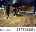 A tenor saxophone rests on the stage floor beneath a grand piano. 137898861