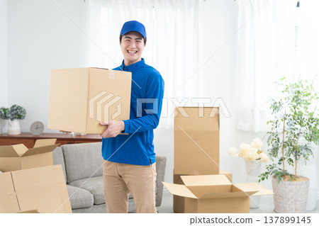 A smiling moving company employee holding cardboard boxes. A smiling moving company employee holding cardboard boxes. 137899145