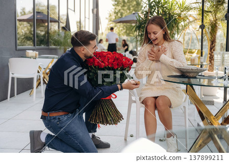 On the knee, shocked, surprised. Man made proposal for his girlfriend in the restaurant outdoors On the knee, shocked, surprised. Man made proposal for his girlfriend in the restaurant outdoors 137899211