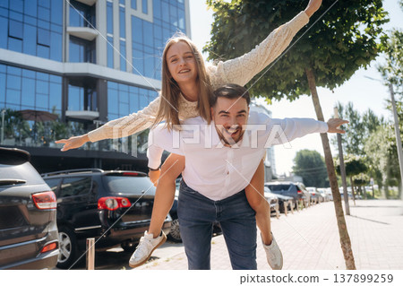 Woman is sitting on man, having fun. Happy couple together outdoors 137899259