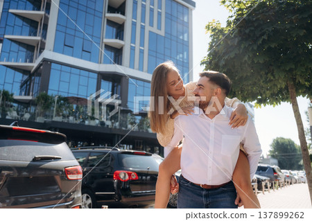 Holding woman on the back, having fun. Happy couple together outdoors 137899262