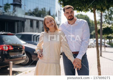 Standing against the cars and building. Happy couple together outdoors Standing against the cars and building. Happy couple together outdoors 137899271