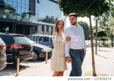 Standing against the cars and building. Happy couple together outdoors Standing against the cars and building. Happy couple together outdoors 137899274