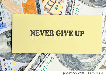 Yellow Never Give Up message on scattered US dollar banknotes, symbolizing enduring financial drive Yellow Never Give Up message on scattered US dollar banknotes, symbolizing enduring financial drive 137899331