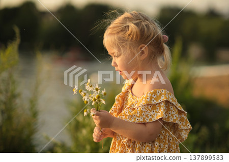 heartfelt smile of girl holding daisies, set against simple park background, advocates for a return to simpler, less materialistic values. benefits of a minimalist lifestyle or simple living. 137899583