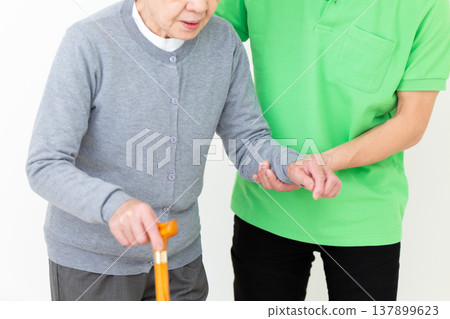 Care workers assisting elderly people with mobility issues. 137899623