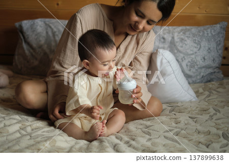 With a delicate balance of love and care, a mother's lips meet her baby's feet, an act that resonates warmth and trust, beautifully portrayed in a close-up With a delicate balance of love and care, a mother's lips meet her baby's feet, an act that resonates warmth and trust, beautifully portrayed in a close-up 137899638