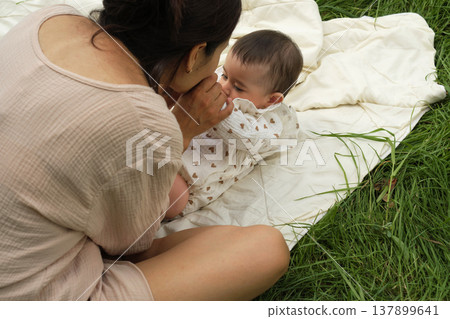 Coziness and care define this scene, a mother and child in a quiet cuddle, surrounded by soft textures. Showcases the gentle spirit of parenting. 137899641