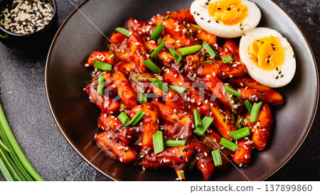 Tteokbokki, Teopokki fried rice cake in black bowl. Tteokbokki, Teopokki fried rice cake in black bowl. 137899860