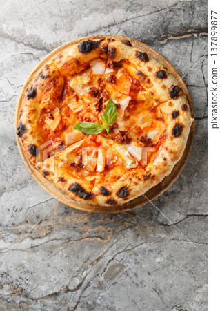 Charred pizza with smoked chicken, brie cheese and sun-dried tomatoes close-up on a wooden board. Vertical top view 137899877