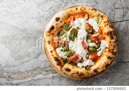 Delicious authentic pizza with stracciatella cheese, pesto, ham and cherry tomatoes close-up on a wooden board. Horizontal top view Delicious authentic pizza with stracciatella cheese, pesto, ham and cherry tomatoes close-up on a wooden board. Horizontal top view 137899885