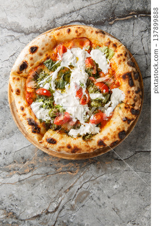 Italian Pizza with stracciatella cheese, pesto, ham and cherry tomatoes close-up on a wooden board. Vertical top view Italian Pizza with stracciatella cheese, pesto, ham and cherry tomatoes close-up on a wooden board. Vertical top view 137899888