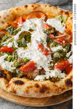 Pizza with stracciatella cheese, pesto, ham and tomatoes close-up on a wooden board. Vertical Pizza with stracciatella cheese, pesto, ham and tomatoes close-up on a wooden board. Vertical 137899895