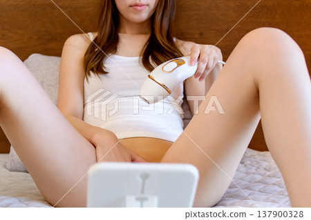 Young women doing VIO (bikini area) hair removal themselves: Home hair removal device, Trimming Up Young women doing VIO (bikini area) hair removal themselves: Home hair removal device, Trimming Up 137900328
