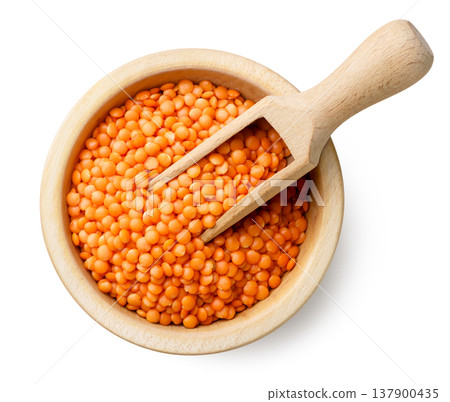 Red lentils in a wooden plate with a spatula on a white background. Top view 137900435