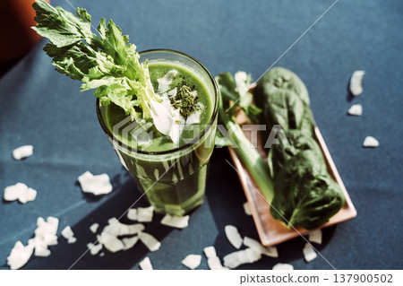 A healthy green smoothie made with fresh celery , standing on a table with a turquoise tablecloth. 137900502