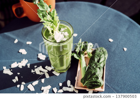 A healthy green smoothie made with fresh celery , standing on a table with a turquoise tablecloth. A healthy green smoothie made with fresh celery , standing on a table with a turquoise tablecloth. 137900503