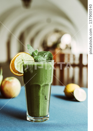 A healthy green smoothie made with fresh spinach, standing on a table with a turquoise tablecloth A healthy green smoothie made with fresh spinach, standing on a table with a turquoise tablecloth 137900540