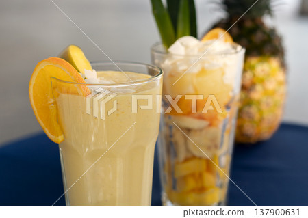 Tasty mango papaya and pineapple smoothie in the glass, standing on the table with blury background. Tasty mango papaya and pineapple smoothie in the glass, standing on the table with blury background. 137900631