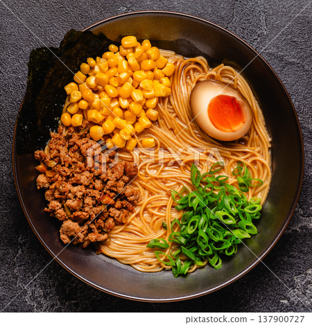 A bowl of ramen with noodles, meat and green onions. 137900727