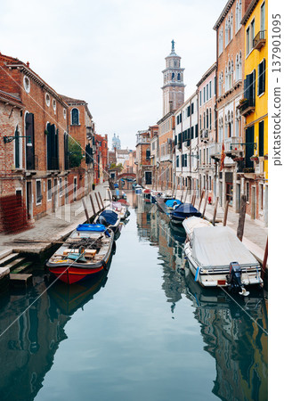 Boats docked in a canal next to buildings in Venice during a cloudy day 137901095