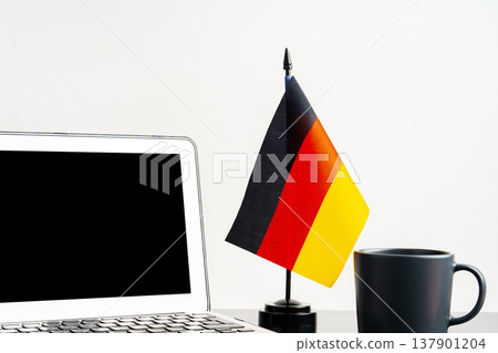 Small German flag next to laptop and mug on a desk Small German flag next to laptop and mug on a desk 137901204
