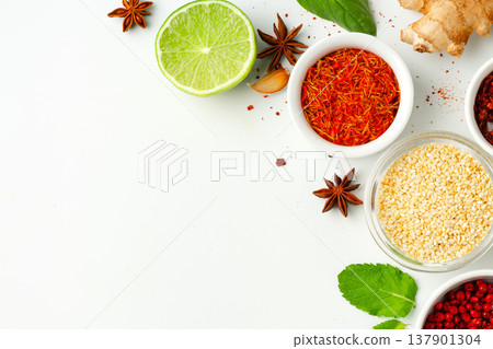 Spices and herbs arranged on a white surface for cooking and food preparation Spices and herbs arranged on a white surface for cooking and food preparation 137901304