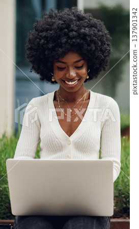 Woman works on laptop outside in a garden during daytime Woman works on laptop outside in a garden during daytime 137901342