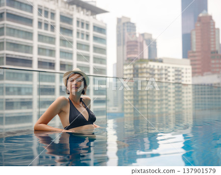 Young woman relaxing by the pool at a Kuala Lumpur hotel Young woman relaxing by the pool at a Kuala Lumpur hotel 137901579