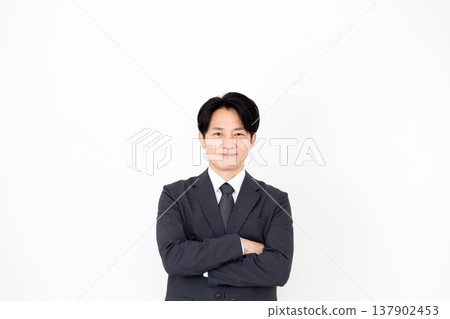 一位身穿西裝、雙手交叉的中年商人。 137902453
