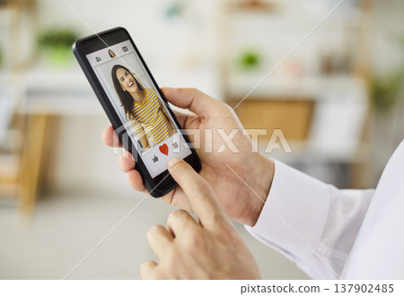 Person using smartphone dating app to like a profile with heart icon closeup 137902485