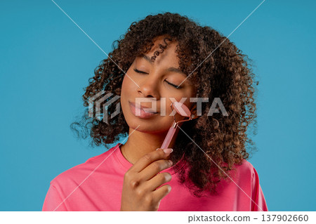 Charming African Woman Doing Face Massage With Rose Quartz Stone Roller Firmer 137902660