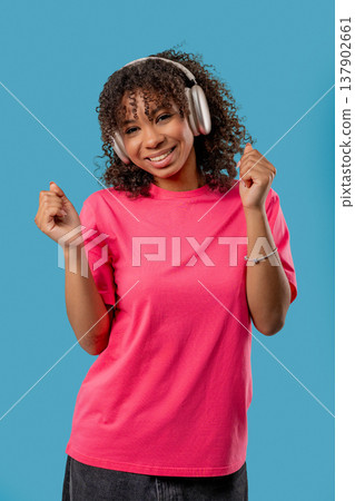 African Pretty Woman Listening Music, Dances With Wireless Headphones On Blue. Vertical photo African Pretty Woman Listening Music, Dances With Wireless Headphones On Blue. Vertical photo 137902661