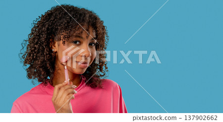 Teenage Girl doing Face Massage with Rose Quartz Stone Roller for Firmer, Smoother Skin. Facial Self Care, Real body, diversity, inclusive, authentic. 137902662