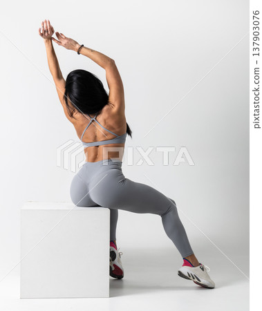 Athletic woman posing in gray sports bra leggings on a white studio background Athletic woman posing in gray sports bra leggings on a white studio background 137903076