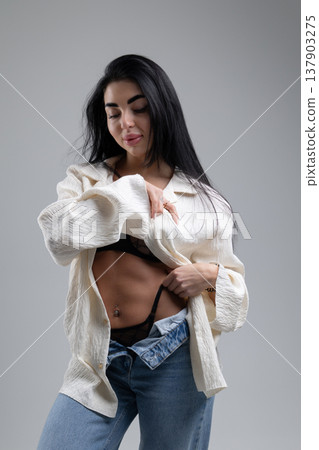 Attractive woman undressing, wearing lingerie and jeans, white studio background 137903275
