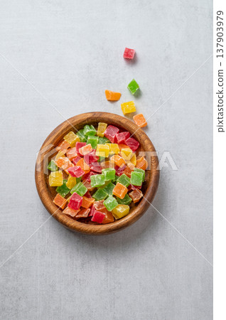 Candied mix fruit in a wooden bowl on a light textured background. Candied mix fruit in a wooden bowl on a light textured background. 137903979