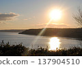 The photograph captures a breathtaking view of a sea bay and autumn forest on the Kuril Islands during sunset on a sunny day. 137904510