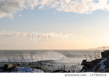 The breathtaking coastline of a Kuril Islands bay glistens at sunset on a sunny winter day. 137904518