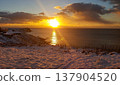 A stunning sunrise casts golden light over a snowy coastline in the Kuril Islands. 137904520