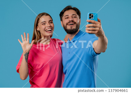 Young Happy Couple Making Selfie With Smartphone On Blue Studio Background 137904661