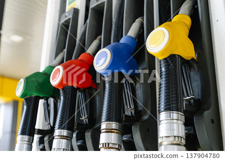 Fuel pump nozzles hanging at a modern gas station during a period of high oil prices. A conceptual photography showcasing the global energy crisis, increasing gasoline costs 137904780