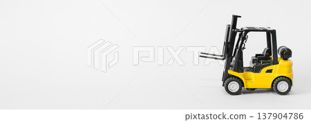 Forklift truck isolated on a blue background as a logic concept of warehouse storage. Conceptual photography showing a miniature toy loader symbolizing supply chain and logistics management with Forklift truck isolated on a blue background as a logic concept of warehouse storage. Conceptual photography showing a miniature toy loader symbolizing supply chain and logistics management with 137904786