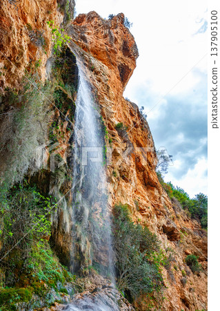 A Serene Waterfall Cascades Over Rocky Cliffs Into a Tranquil Pool Surrounded by Lush Greenery 137905100