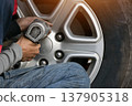 A mechanic using a tool to remove a car wheel. 137905318