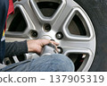 A mechanic using a tool to remove a car wheel. 137905319